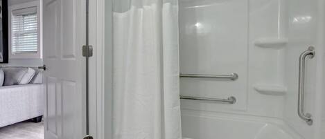 A bathroom with a bathtub, a shower with glass doors, and a white door.