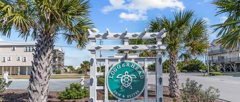 Naamplaatje voor Loggerhead Inn & Suites met een logo van een zeeschildpad, omringd door palmbomen en een heldere lucht.