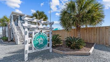 Una valla de madera, una palmera y un letrero del Loggerhead Inn & Suites.