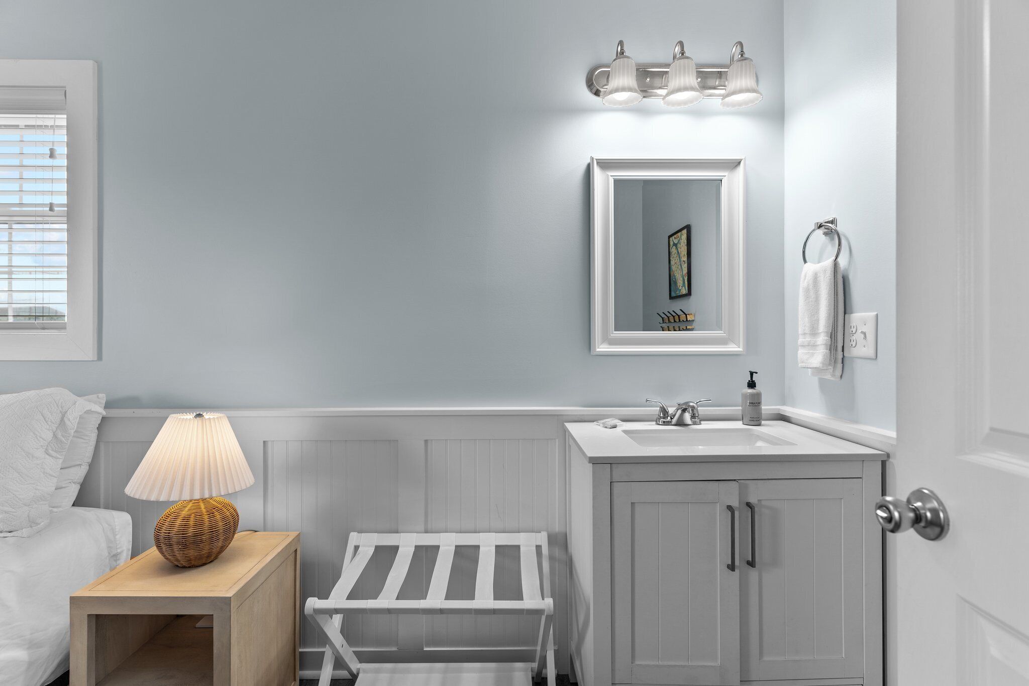 Une salle de bain avec un lavabo blanc, un miroir et un porte-serviettes.