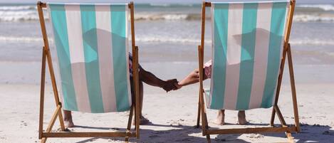 Twee strandstoelen met gestreepte bekleding gericht op de zee.