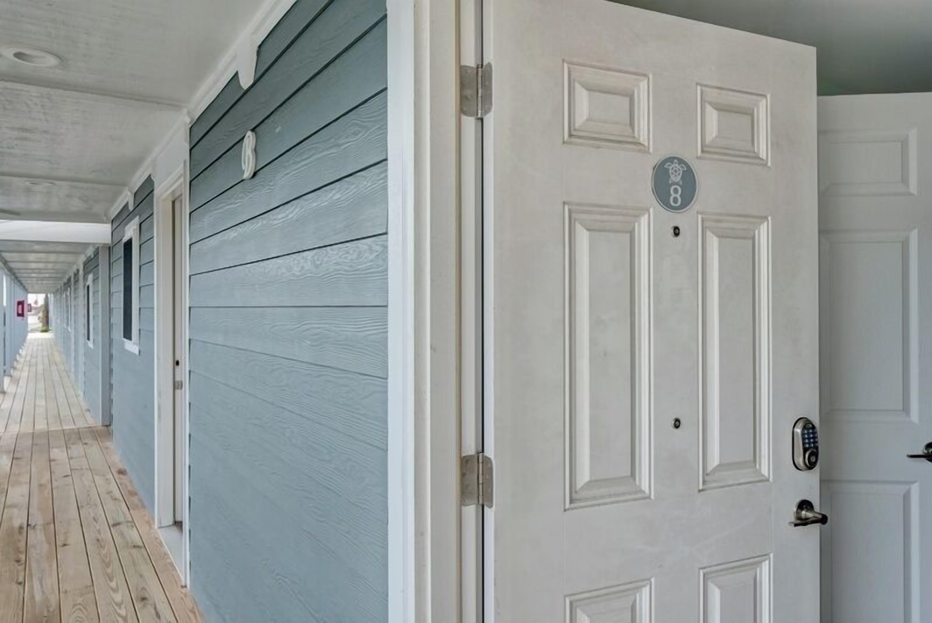 A hallway with a wooden floor and a white door with a number plate.