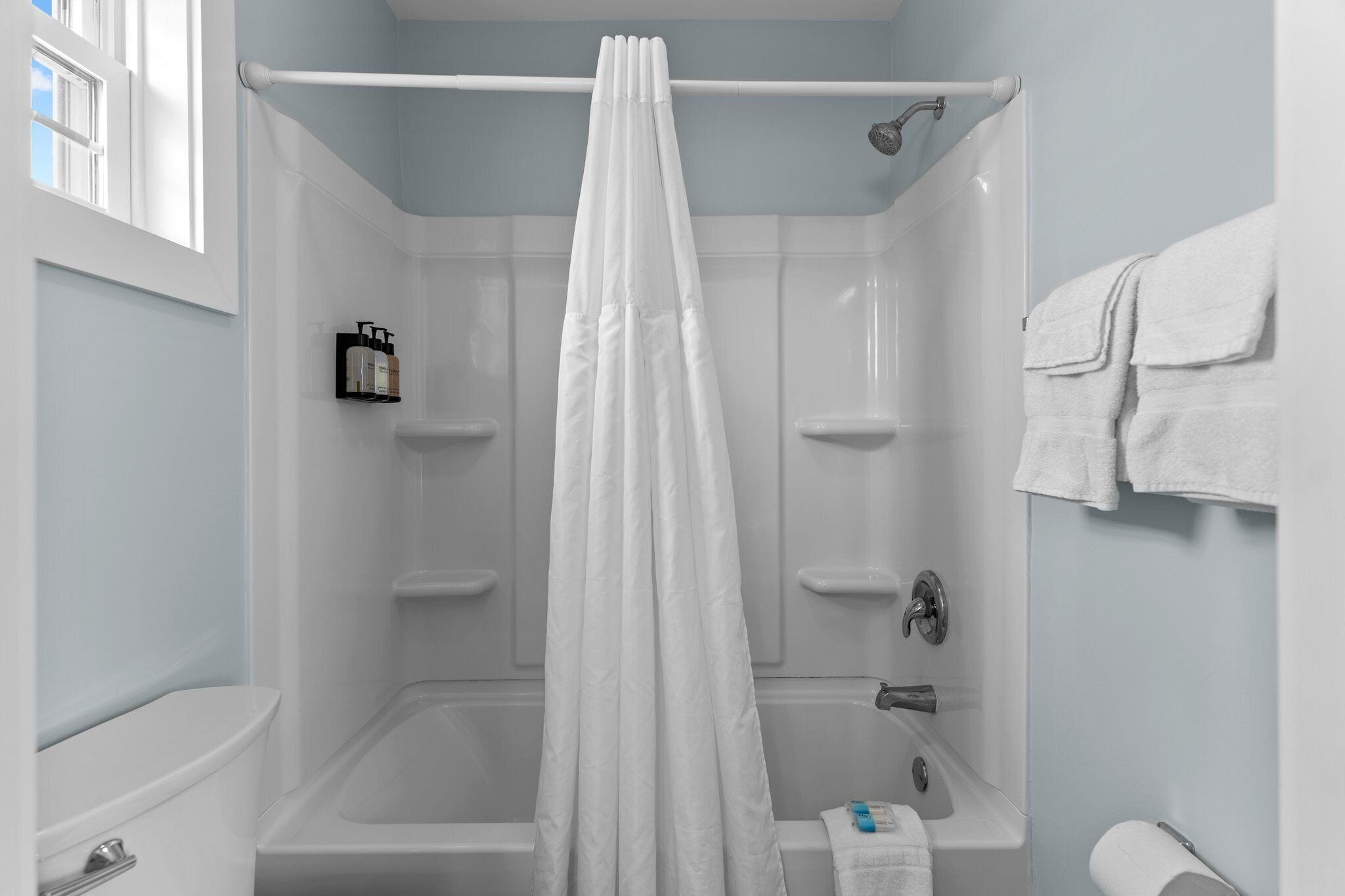 A bathroom with a bathtub, shower, and toilet.