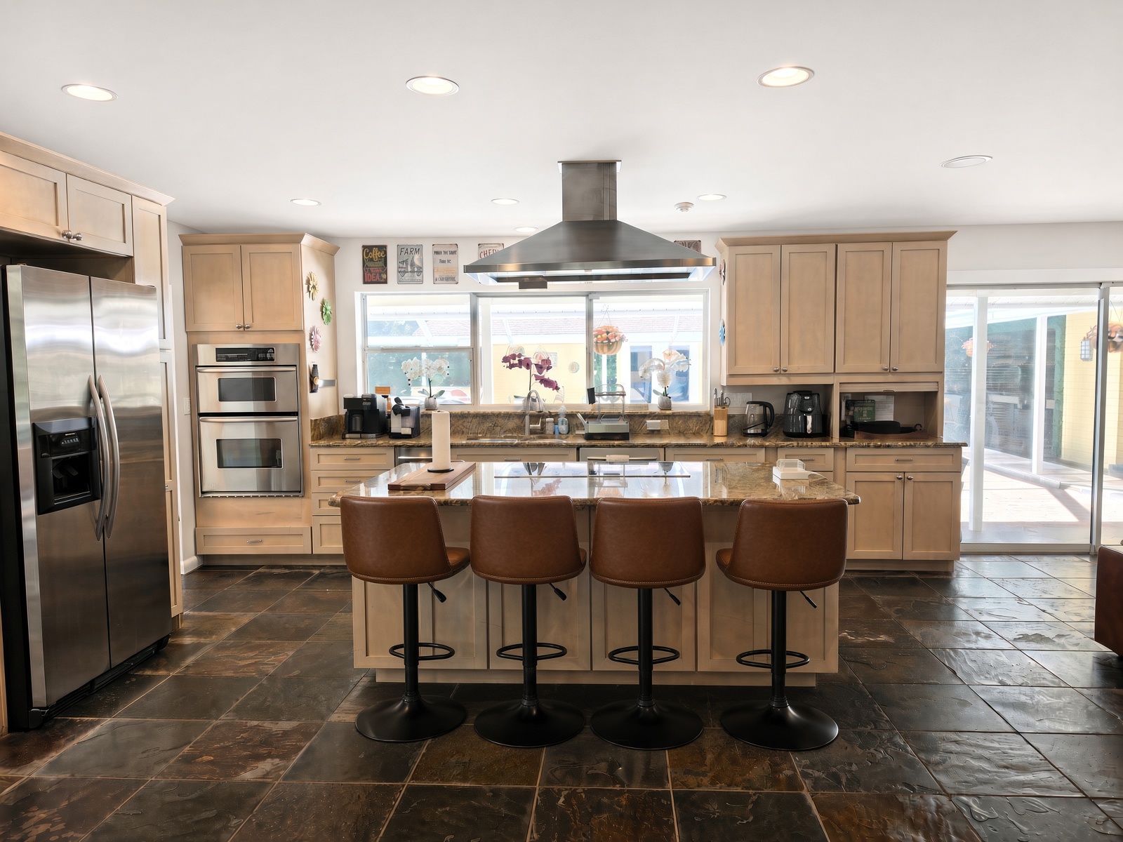 A modern kitchen with a central island, stainless steel appliances, and a large window.