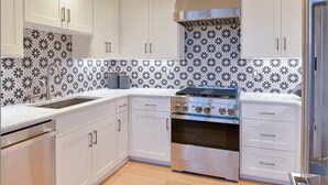 A modern kitchen with white cabinets, a stainless steel stove, and patterned backsplash.