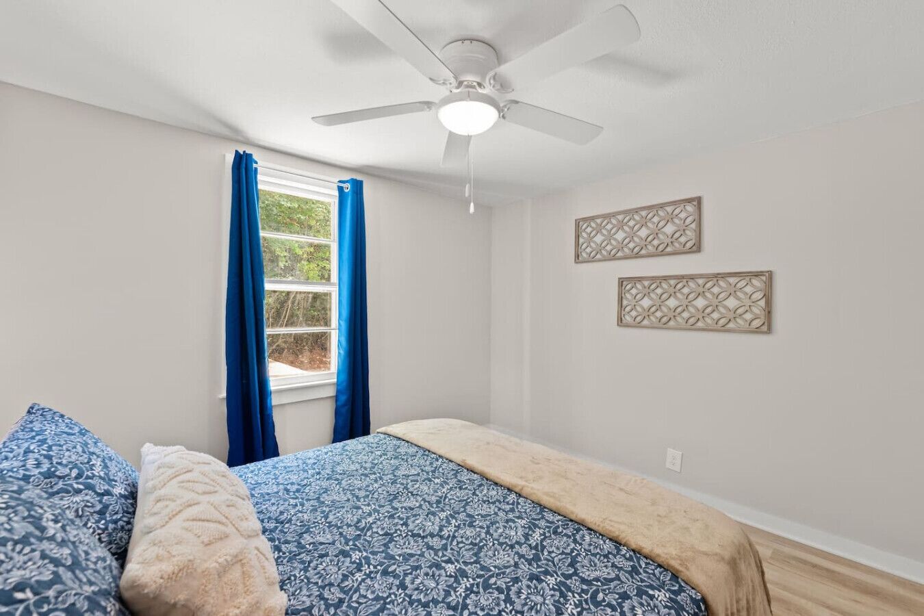 Ein Schlafzimmer mit einem Bett, einem Deckenventilator und zwei Wandbildern.