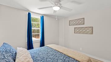 Ein Schlafzimmer mit einem Bett, einem Deckenventilator und zwei Wandbildern.