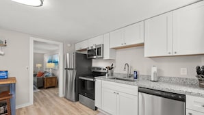 A modern kitchen with stainless steel appliances, white cabinetry, and a granite countertop. - Downtown Dahlonega Destination - Dog Friendly (Dahlonega)