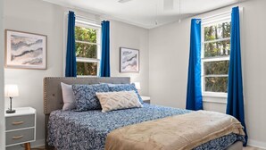 A bedroom with a bed, bedside tables, and two windows with curtains. - Downtown Dahlonega Destination - Dog Friendly (Dahlonega)