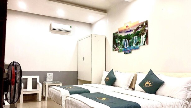 A hotel room with two beds, a wardrobe, a desk, and an air conditioning unit. - Holiday Hotel 2 (Hai Phong)