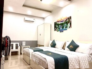 A hotel room with two beds, a wardrobe, a desk, and an air conditioning unit. - Holiday Hotel 2 (Hai Phong)