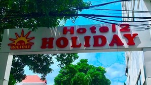 A sign for 'Hotel Holiday' with a sun logo and a red roof in the background. - Holiday Hotel 2 (Hai Phong)