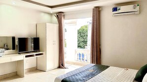 A hotel room with a bed, a television, a desk, and a window with curtains. - Holiday Hotel 2 (Hai Phong)