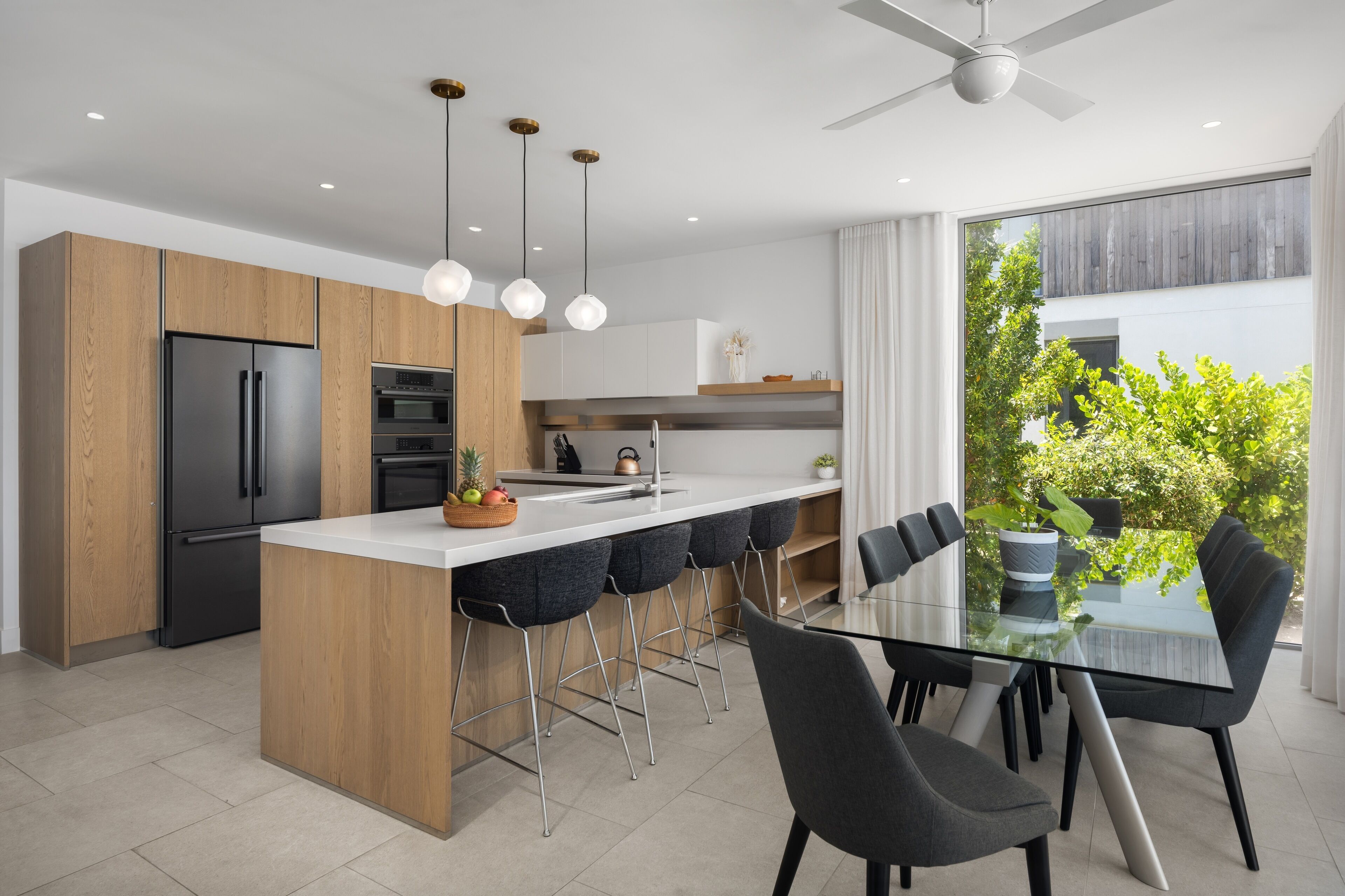 Una cocina moderna con una isla central, taburetes de bar y una mesa de comedor con sillas.