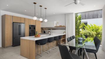Una cocina moderna con una isla central, taburetes de bar y una mesa de comedor con sillas.