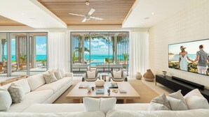 A modern living room with a large TV, comfortable seating, and a view of the ocean. - South Bank (Providenciales)
