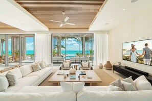 Een moderne woonkamer met een grote televisie, comfortabele zitplaatsen en uitzicht op zee.
