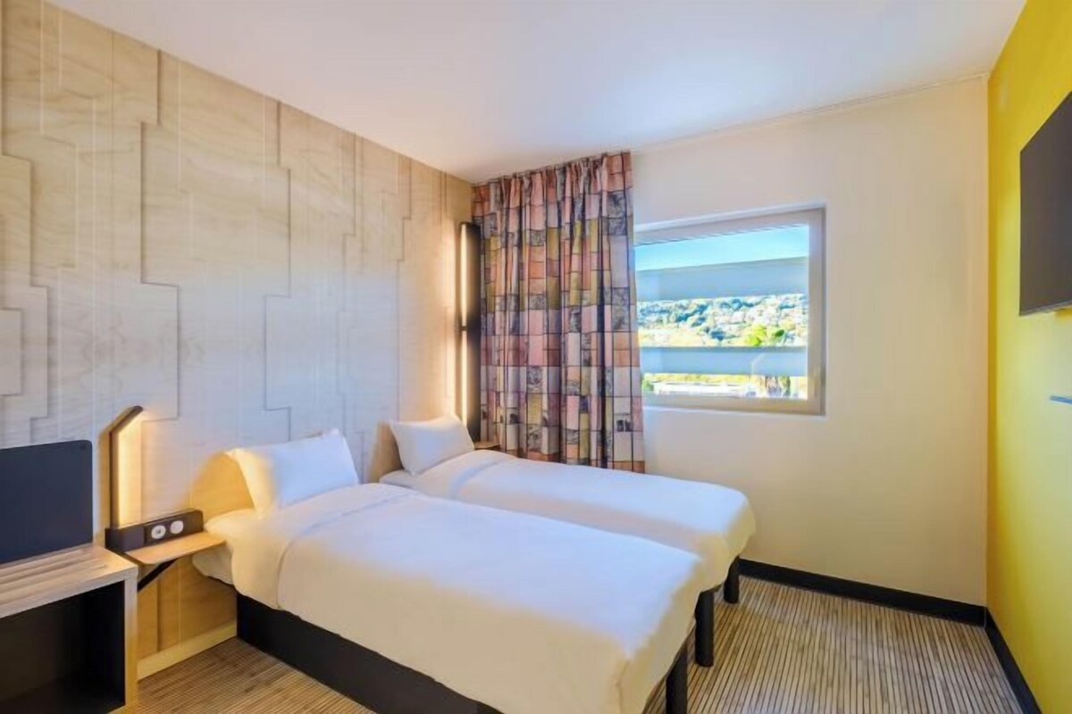 Ett hotellrum med en säng, en tv och ett fönster med utsikt.
