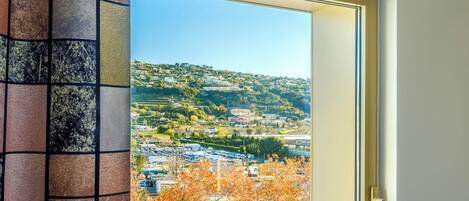 Janela com vista para uma cidade, edifícios e árvores.