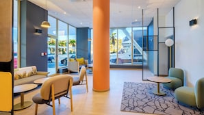 A modern hotel lobby with a large orange pillar, seating areas, and large windows offering views of the outside. - B&B HOTEL Nice Stade Riviera (Nice)