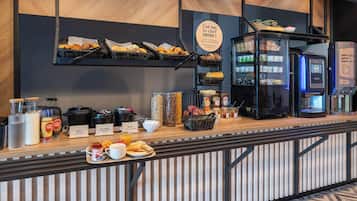 Un comptoir de petit-déjeuner avec divers aliments, une machine à café et un réfrigérateur.