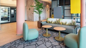 A modern lobby with a seating area, a vending machine, and a large plant. - B&B HOTEL Massieux Genay (Genay)