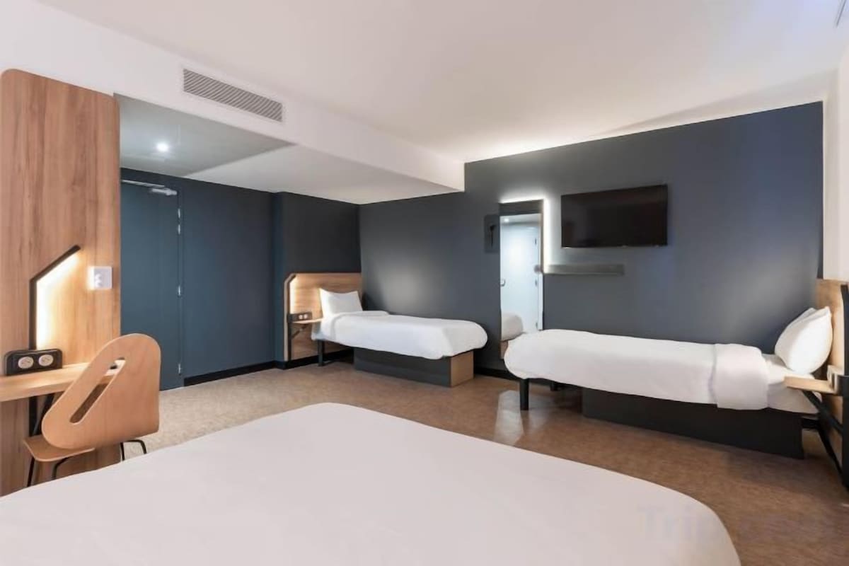 Une chambre d’hôtel avec un grand lit, deux tables de chevet, un bureau et une chaise.
