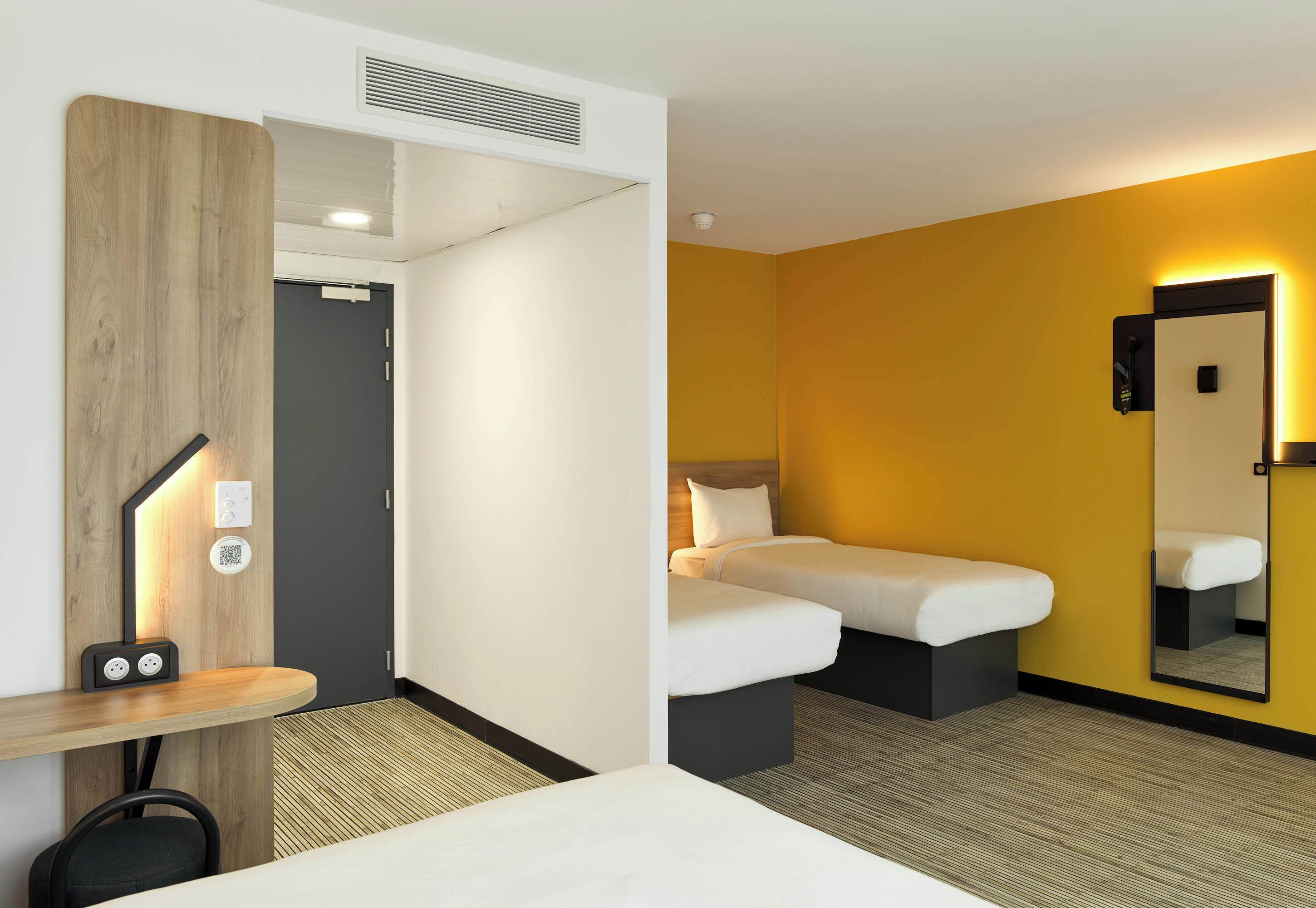 Een hotelkamer met een bed, nachtkastje en spiegel.