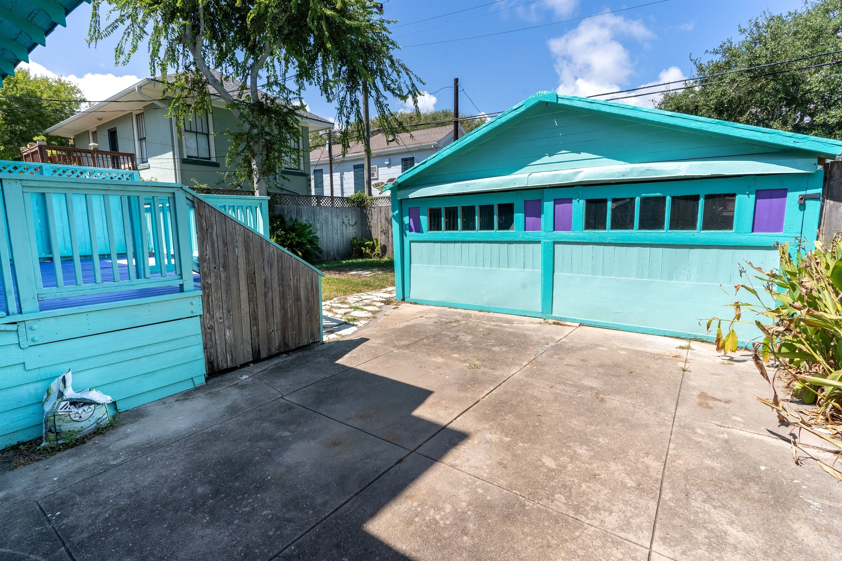 Un quartier résidentiel avec un garage turquoise, une clôture en bois et une allée en béton.