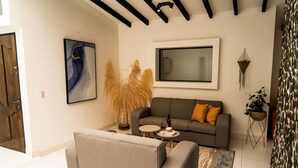 A modern living room with a grey sofa, a smaller armchair, a coffee table, and a large abstract painting.