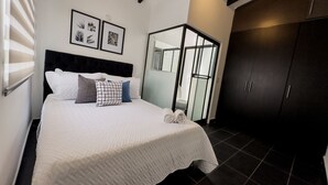 A bedroom with a large bed, a dark headboard, and a wardrobe.