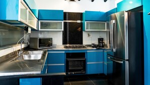 A modern kitchen with blue cabinets, stainless steel appliances, and a black countertop.