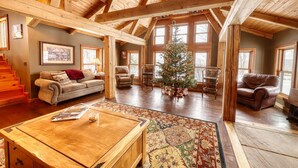Ein geräumiges Wohnzimmer mit Holzbalkendecke, Weihnachtsbaum und Kamin.