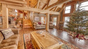 Ein geräumiges Wohnzimmer mit Kamin, Holzbalken, einem Weihnachtsbaum und einer gemütlichen Sitzecke.