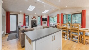 Een moderne keuken met een centraal eiland, een houten eettafel en rode gordijnen.