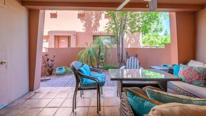 Un patio couvert comprenant une table et des chaises, un canapé et un ventilateur de plafond.