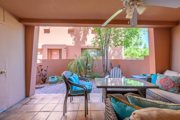 Un patio couvert comprenant une table et des chaises, un canapé et un ventilateur de plafond.