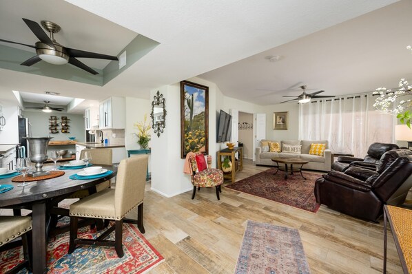 A spacious living area with a dining table, sofas, and a kitchen in the background. - CASA MERLOT-Anasazi Village-Ground floor beautiful condo steps away from Pool. (Phoenix)