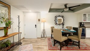 Un coin repas comprenant une table ronde, des chaises, un miroir décoratif et un ventilateur de plafond.
