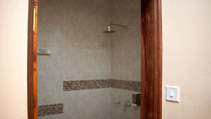 A shower with a tiled wall, a showerhead, and a control panel. - Korongoro Hotel Chemolingot (Chemolingot)