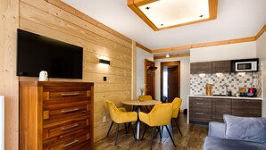Una cocina moderna con armarios de madera, un microondas y un comedor con sillas amarillas.