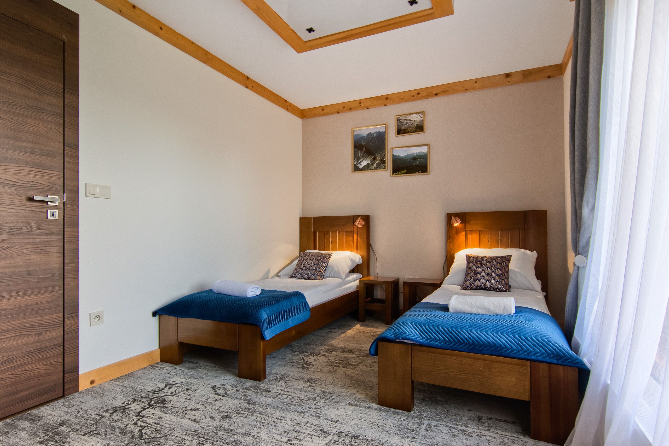 Una habitación de hotel con dos camas de madera, techo de madera y suelo alfombrado.