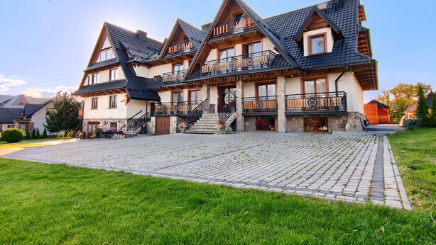 Un edificio grande de varios pisos con fachada de piedra, varios balcones y una escalera central.