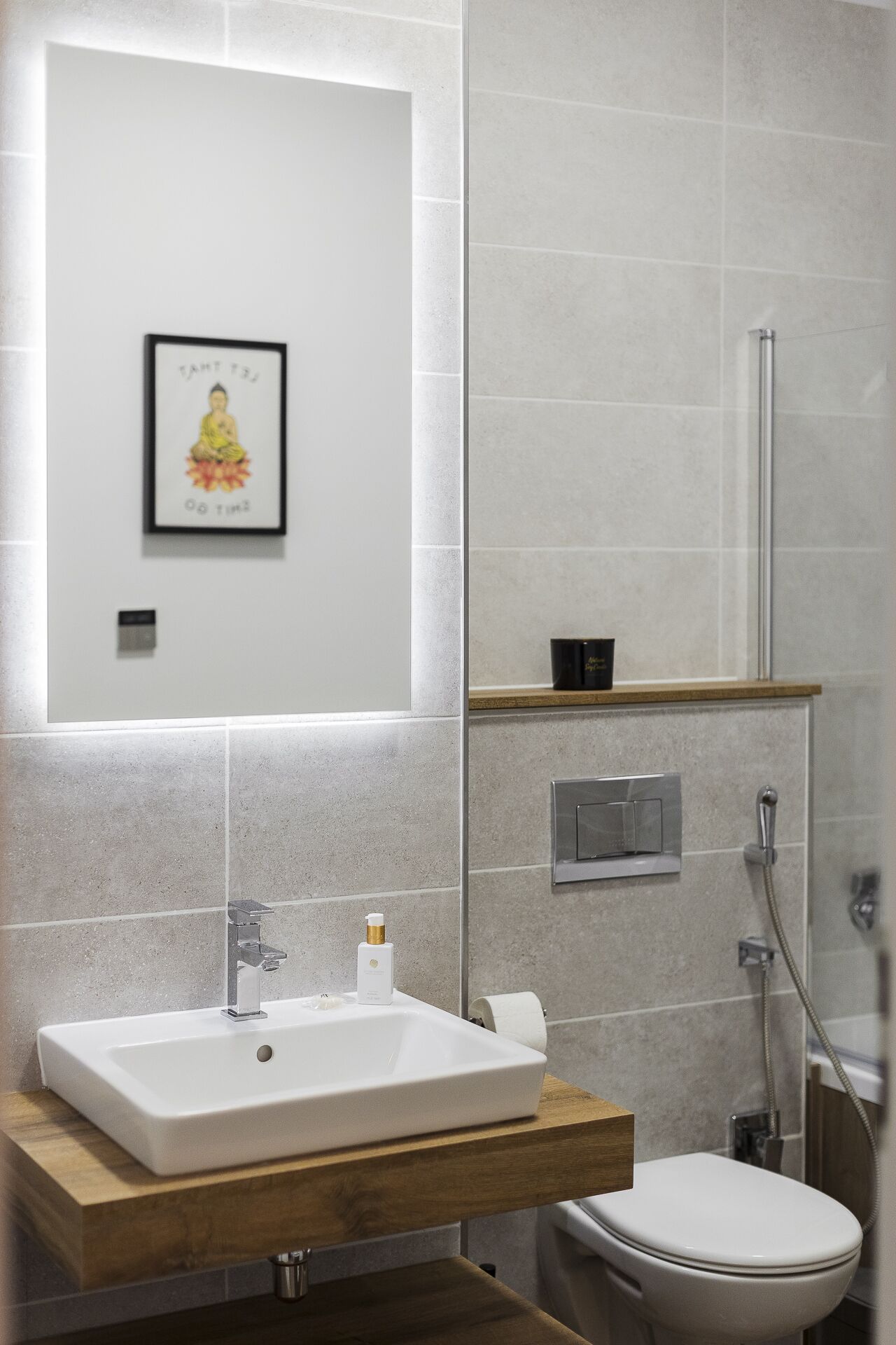 Ein modernes Badezimmer mit Waschbecken, Toilette und Dusche. Darüber hängt ein Bild in einem Rahmen an der Wand.