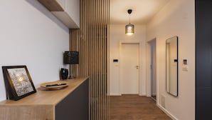 A modern hallway with a wooden reception desk, a framed picture, a black lamp, and a pendant light. - Zoe Apartment (Timisoara)
