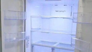 Un refrigerador de acero inoxidable con varios estantes transparentes y un compartimento congelador.