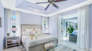 Une chambre moderne avec un grand lit, un ventilateur de plafond et une vue sur l’extérieur.