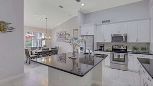 Una cocina moderna con armarios blancos, electrodomésticos de acero inoxidable y una isla central.