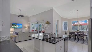 Una cocina moderna con una isla central, un comedor con mesa y sillas, y un ventanal que ofrece vistas al exterior.