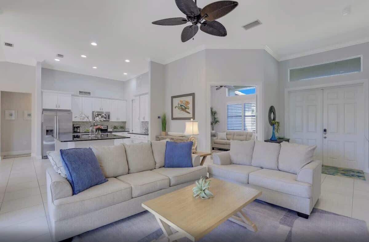 A spacious living area with a large sofa set, a coffee table, and a ceiling fan.